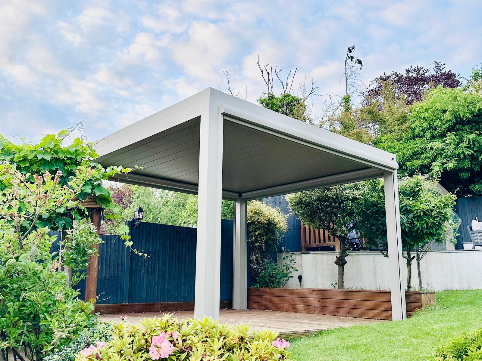 Pergola bioclimatique aluminium autoportante à lames fermées dans un jardin